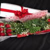 Long bouquet of red roses with baby's breath and a gift box tied with a red bow