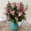 Pink roses and small purple flowers in a turquoise vase