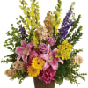 Mixed bouquet with pink lilies, roses, and yellow flowers in a brown vase