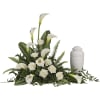 White calla lilies and roses arranged beside a white urn