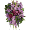 Standing floral spray with purple blooms and pink roses on easel