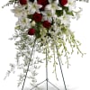 Standing floral spray of red roses and white lilies on an easel