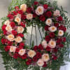 Heart-shaped wreath of red and blush roses on a stand