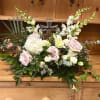 Pastel floral arrangement with roses, lilies, and a cross centerpiece