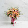 A soft and elegant bouquet designed with warm peach and pastel tones