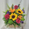 Bright mixed arrangement with sunflowers, orange lilies, pink roses, and purple blooms in a wooden box.