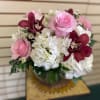 Pink roses and white hydrangeas with burgundy orchids in a glass vase