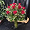 Red roses arranged in a clear glass vase with small white filler flowers