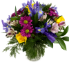Iris, yellow roses, purple daisys, and alstromeria arraned in a glass vase