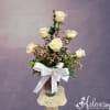 White roses in a glass vase with a white ribbon bow