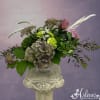 Mixed bouquet with pink roses, green hydrangea, and white filler flowers in a glass vase