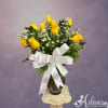 Yellow roses and white daisies in a glass vase with a white ribbon