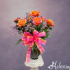 Orange roses in a glass vase with a pink plaid ribbon