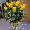 12 long stem yellow roses arranged in a glass vase with assorted