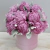 Round pink hatbox arrangement of bright pink peonies with soft silvery foliage