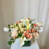 Arrangement of peach roses and white calla lilies in a square glass vase