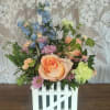 Spring colored blooms inside a white wooden picket fence planter.