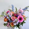 Colorful mixed bouquet in a white vase with pink, orange, blue, and purple blooms