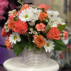 Bouquet of orange roses and white daisies in a striped vase
