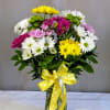 Mixed daisy bouquet in a glass vase with a yellow polka-dot ribbon