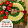 Large white sympathy wreath with red and pink flowers on a stand and a ribbon reading 'Miss you, Grandpa'