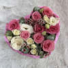 Heart-shaped arrangement of pink and white roses and lisianthus in a pink box