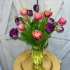 Bouquet of pink and purple tulips in a clear glass vase