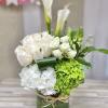 Tall white and green arrangement with calla lilies, roses, and hydrangeas in a glass cylinder vase