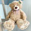 Large plush teddy bear with a plaid bow sitting on a wooden ladder