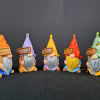 Five colorful gnome figurines holding welcome signs
