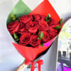 Handheld bouquet of red roses wrapped in red and green paper with a matching red ribbon.