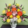 Colorful mixed bouquet in a white vase with a silver bow
