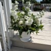 A bouquet of white and green flowers with greenery designed into a