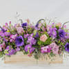 Purple and pink floral arrangement in a wooden box