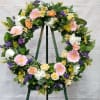 Floral wreath on a stand with pink, white, yellow, and purple flowers
