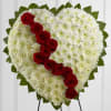 Heart-shaped white floral tribute with a diagonal line of red roses