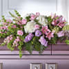 Pink lilies and roses arranged with white hydrangeas on a casket