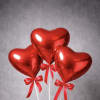 A set of three red heart-shaped balloons on sticks, finished with matching