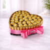 Heart-shaped arrangement of gold-wrapped chocolates with a pink ribbon bow