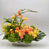 This vibrant, garden-style arrangement blends warm peach roses, sunny yellow tulips, and