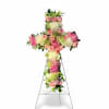 A graceful floral cross featuring soft pink roses, white chrysanthemums, and delicate