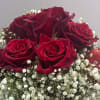 Crafted with half a dozen vibrant red roses, accented with delicate baby&rsquo;s