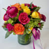 Bright mixed bouquet of roses and ranunculus in a glass vase