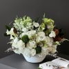This elegant arrangement features a mix of fresh white flowers, including roses