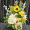 A rustic arrangement made with hydrangeas, sunflowers, roses and delphinium and assorted