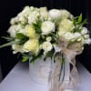 White rose and ranunculus arrangement in a round hatbox with ribbon
