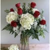 Red roses and white hydrangeas in a clear glass vase