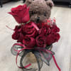 A charming teddy bear holding a bouquet of vibrant red roses adorned