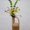A sculptural floral arrangement designed in a tall, long-necked clay pitcher, Juno