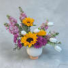 A fun fragrant spring arrangement filled with sunflowers, stock, sweet tulips and